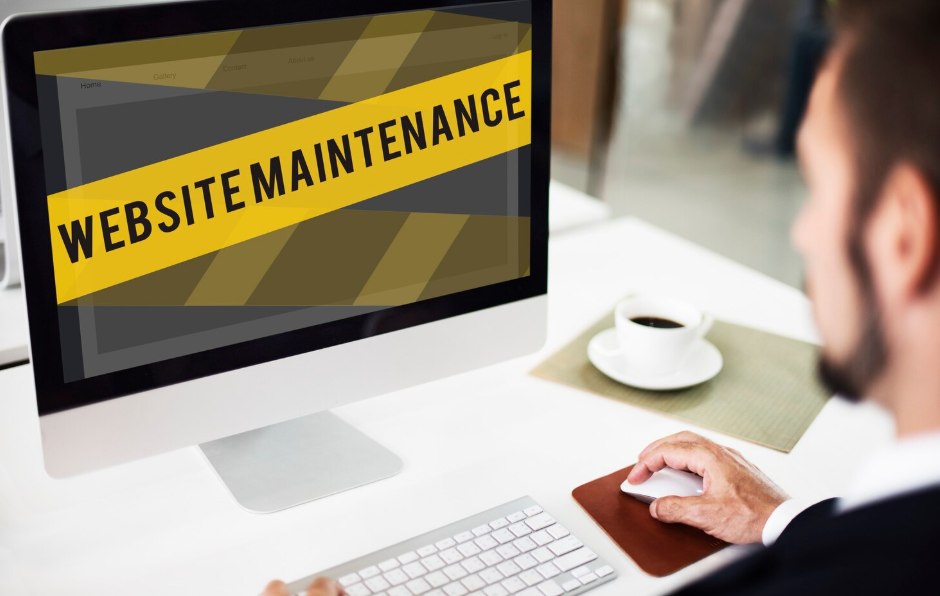 A man looking at a Website Maintenance warning banner on his computer screen